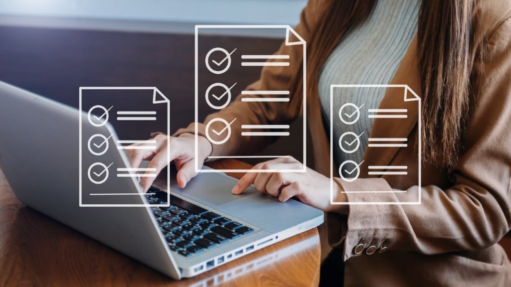 Eine Frau tippt auf ihrem Laptop, davor grafisch dargestellte Icons von Vertragsunterlagen.