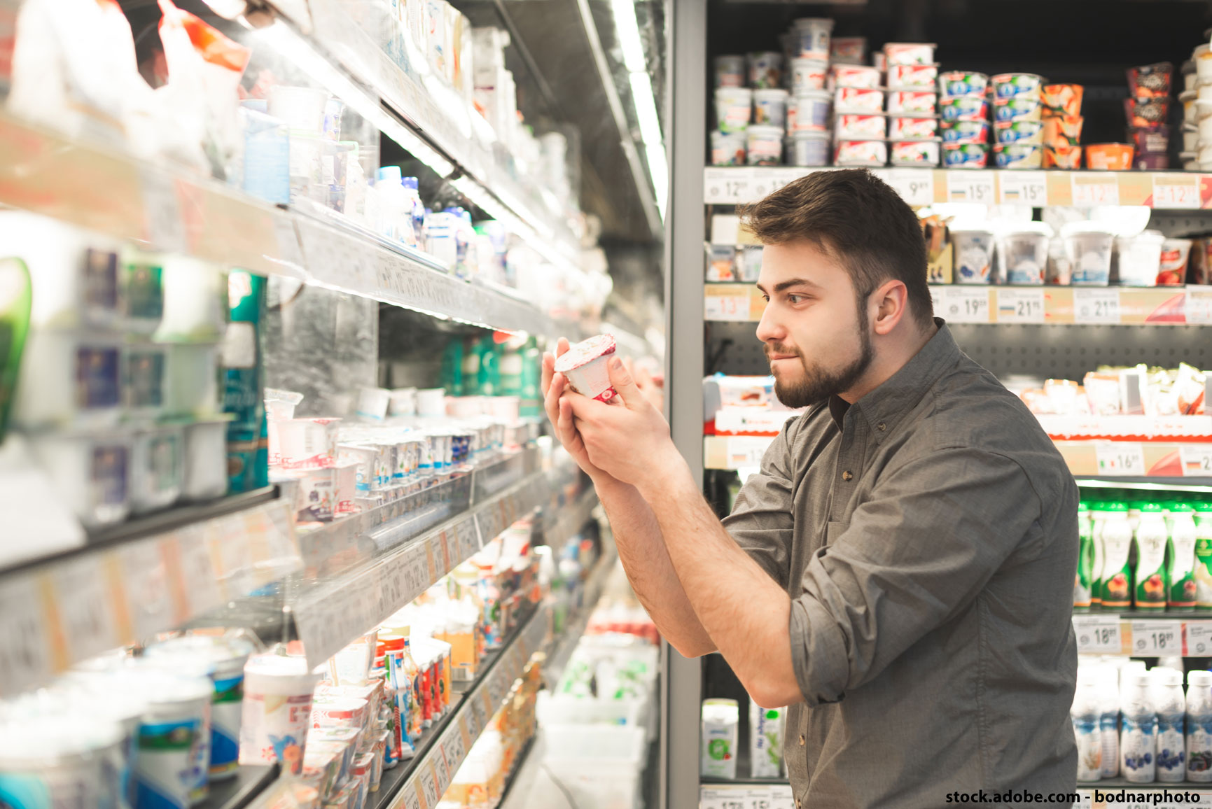 Un homme regarde attentivement l'emballage d'un produit pour connaître sa composition et un éventuel label alimentaire