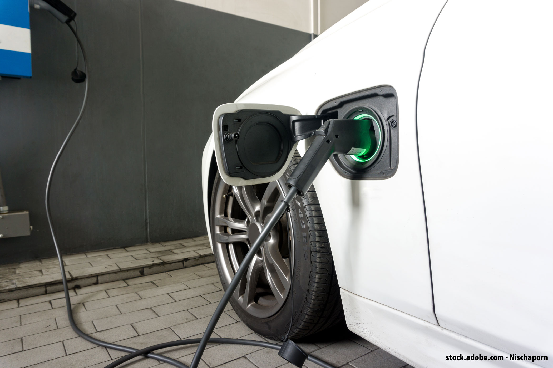 Voiture électrique blanche branchée à une borne de recharge