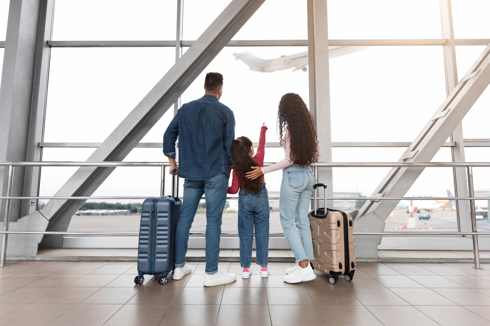 Une famille à l'aéroport qui regarde un avion décoller avant de partir en vacances