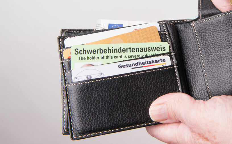 Une carte d'invalidité allemande, le Schwerbehindertenausweis, rangée dans un porte feuille au-dessus de la carte vitale allemande, la Gesundheitskarte
