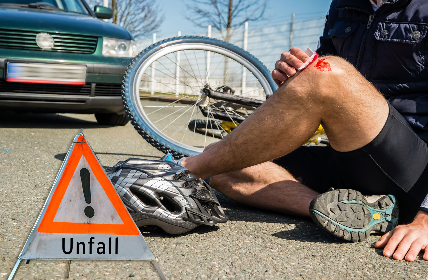 Un cycliste au sol avec le genou qui saigne suite à un accident de vélo