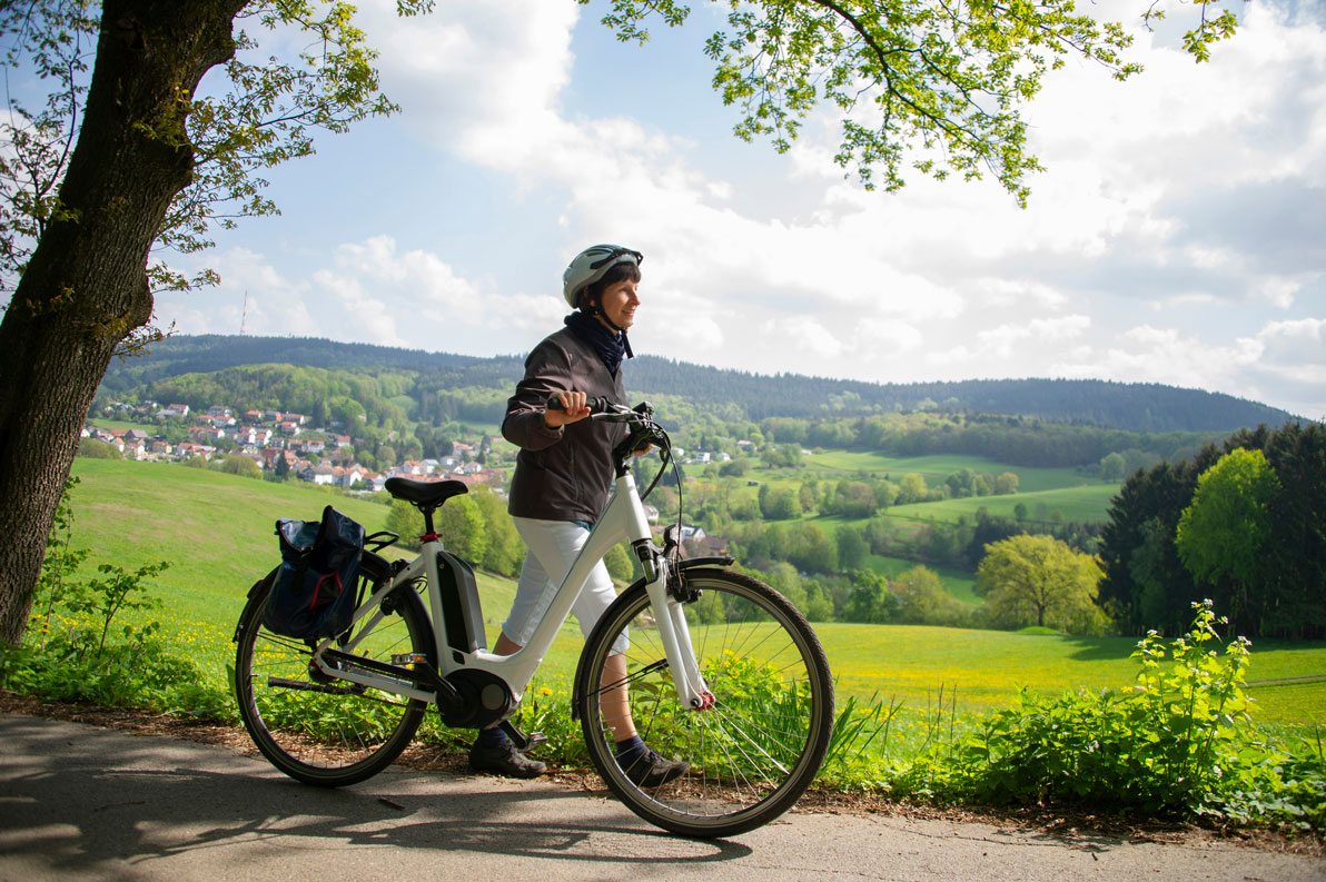 Une cycliste qui pousse son vélo électrique sur une petite route dans la campagne en Allemagne