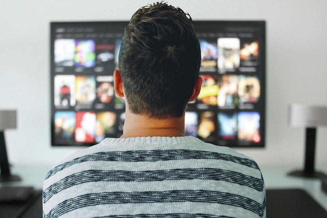 Homme devant une télé montrant un site de streaming