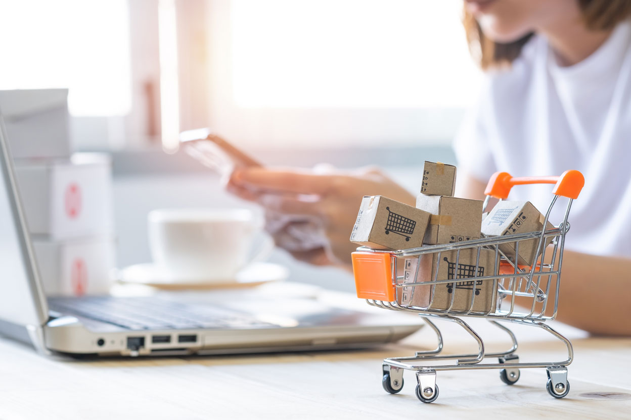 Petit caddie rempli de cartons devant un écran d'ordi