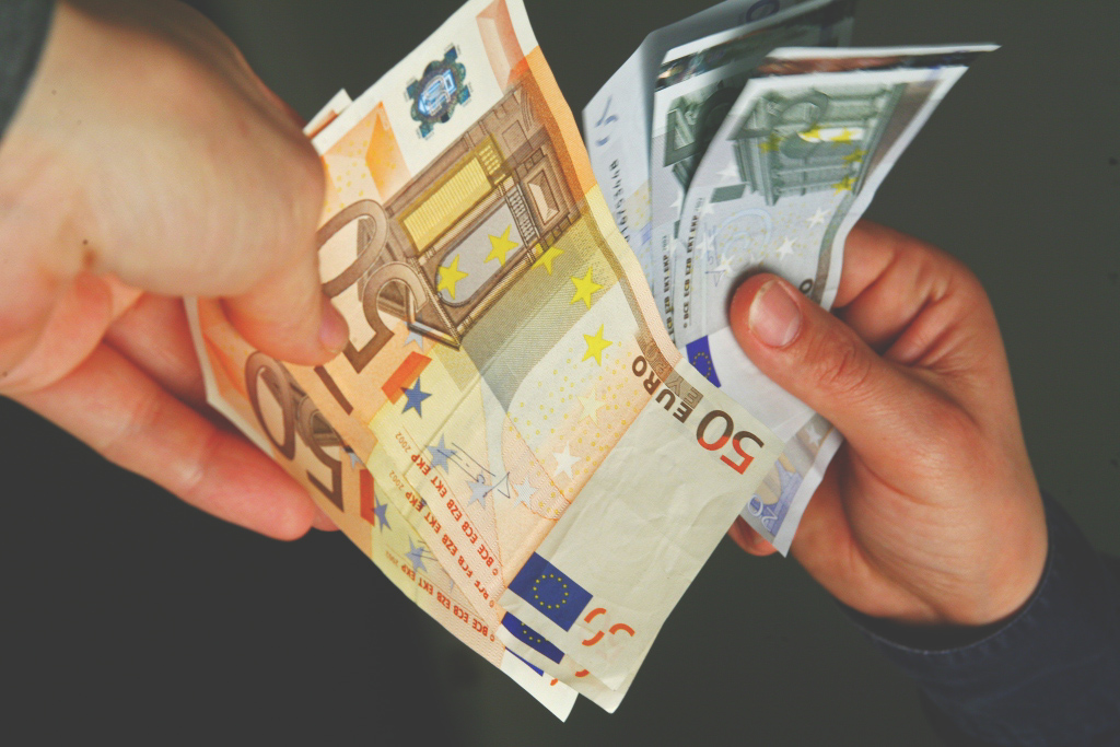 Des mains tenant plusieurs billets en euros