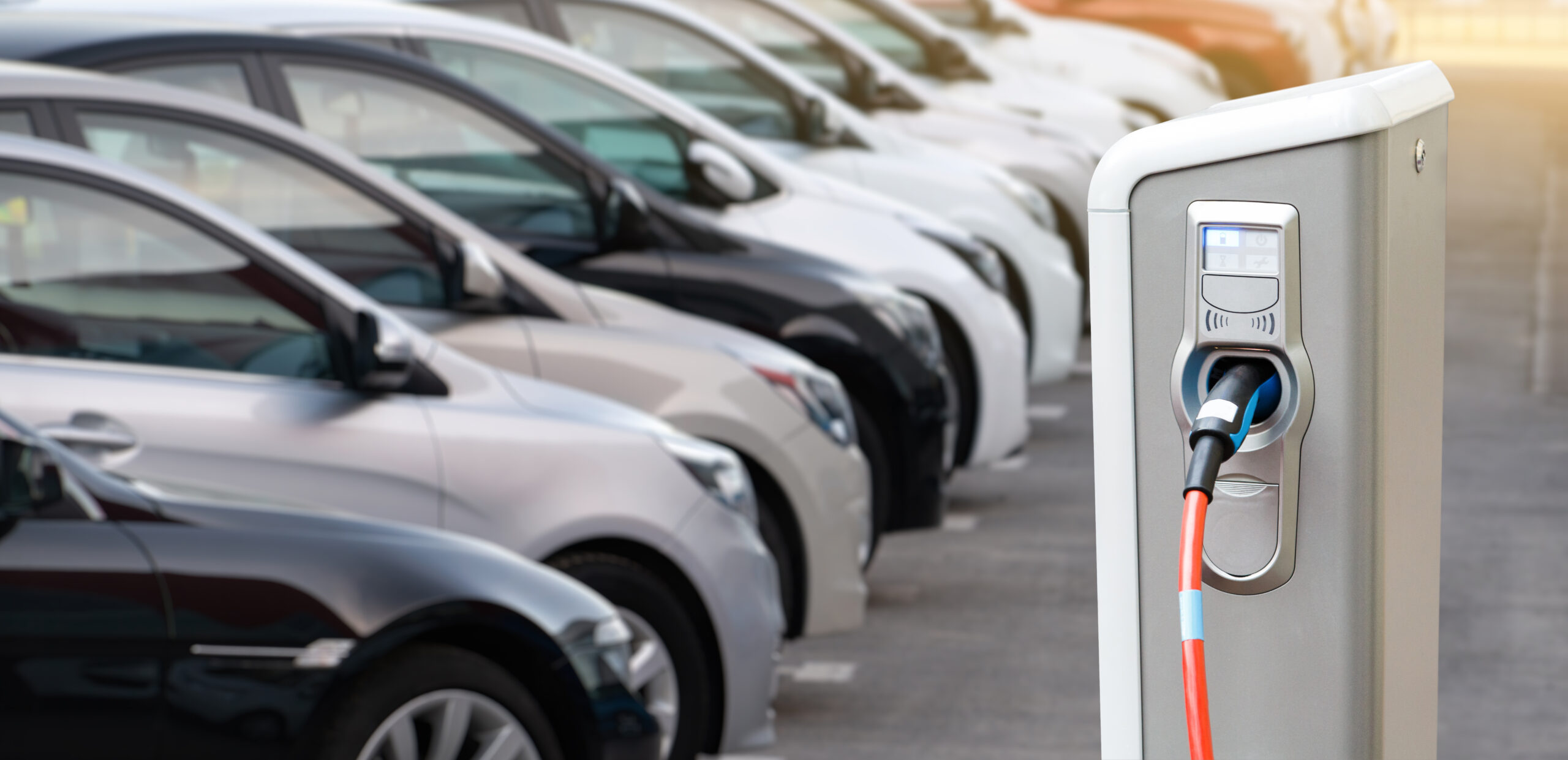 Several cars parked next to another, close to a charging station