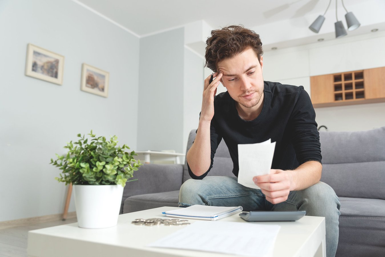 Ein Mann prüft seine Konto-Auszüge und hält sich den Kopf.