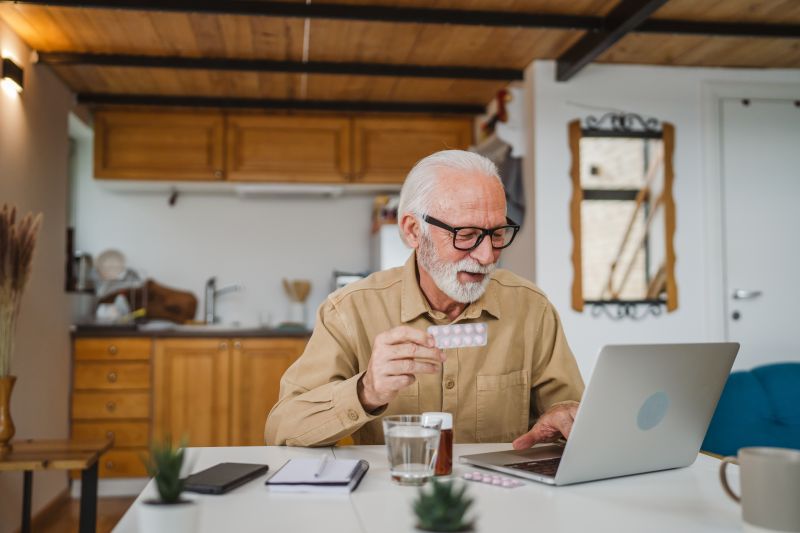 Ein Mann vergleicht seine Tabletten mit einem Produkt aus einer Online-Apotheke.