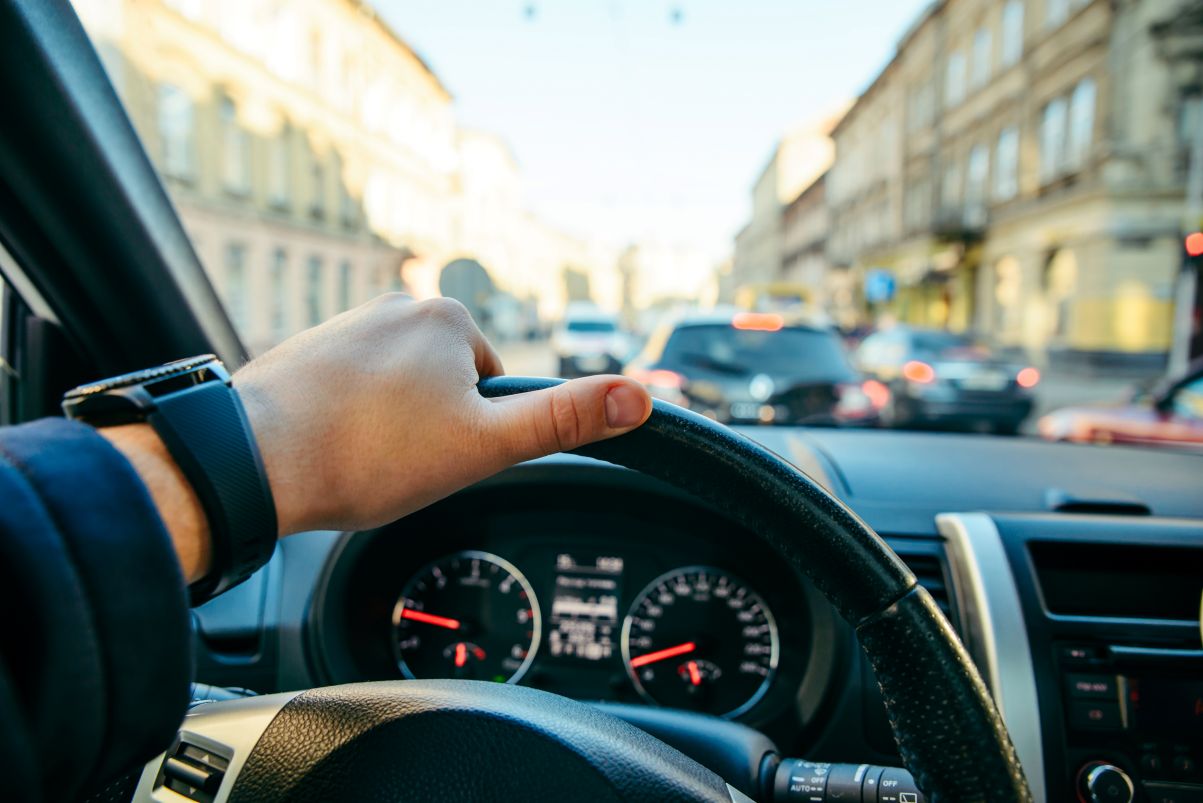 Person steuert Auto im dichten Stadtverkehr.
