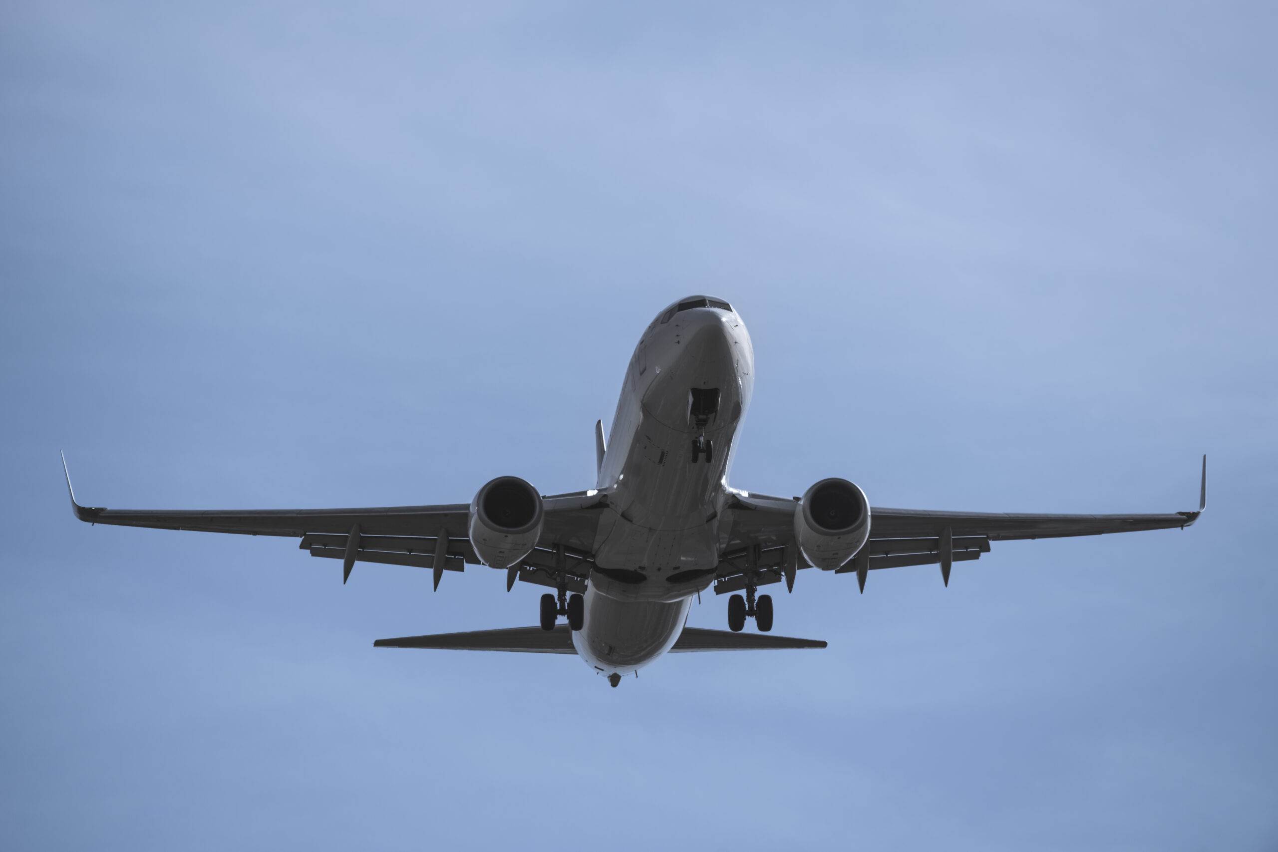 Close-up of an plane in flight, viewed from below against a blue sky
